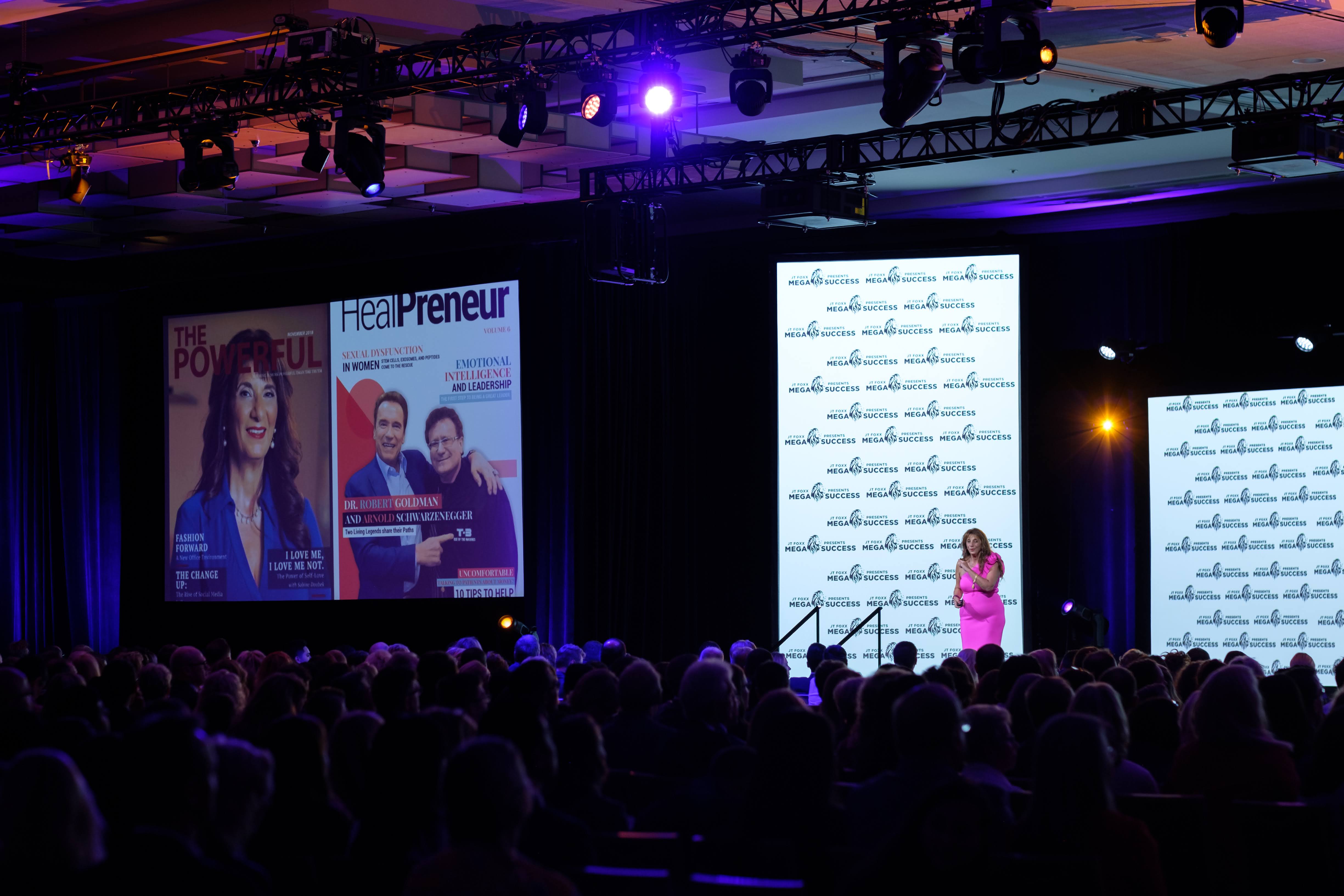 Dr. Dalal Akoury speaking on stage at a Mega Success conference