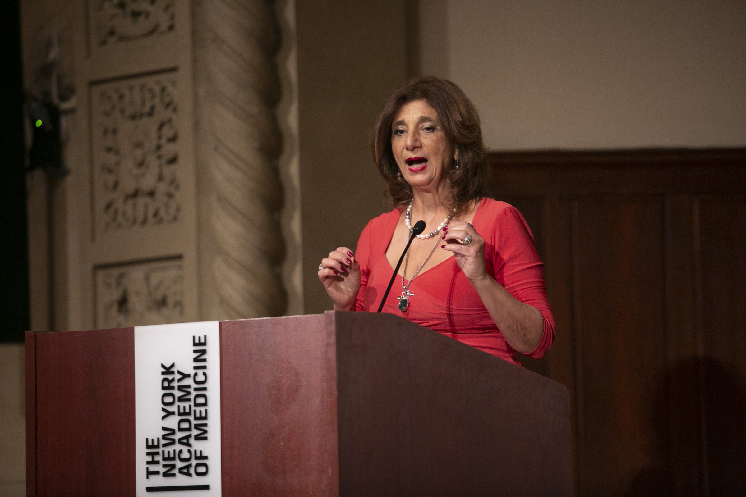 Dr. Dalal Akoury speaking at a podium at the New York Academy of Medicine, addressing fellow physicians