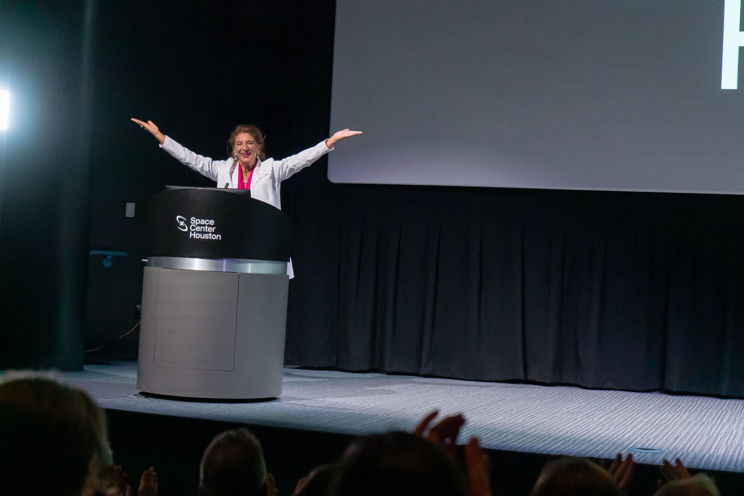 Dr. Dalal Akoury addressing an audience on stage at Space Center Houston